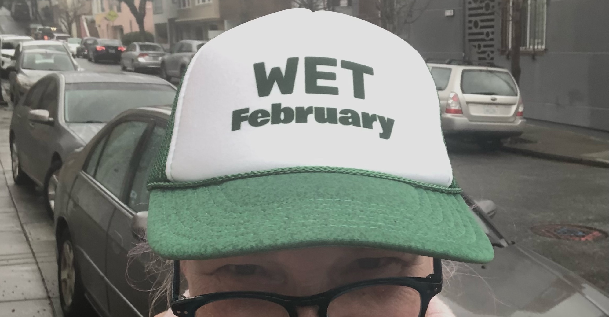 Woman in the rain --wearing a hat reading WET February