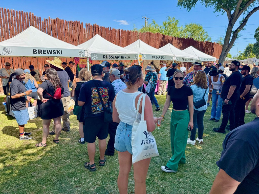 A crowd hanging out at FWIBF in front of popup kiosks marked "Brewski," "Russian River," Breakside," and more.
